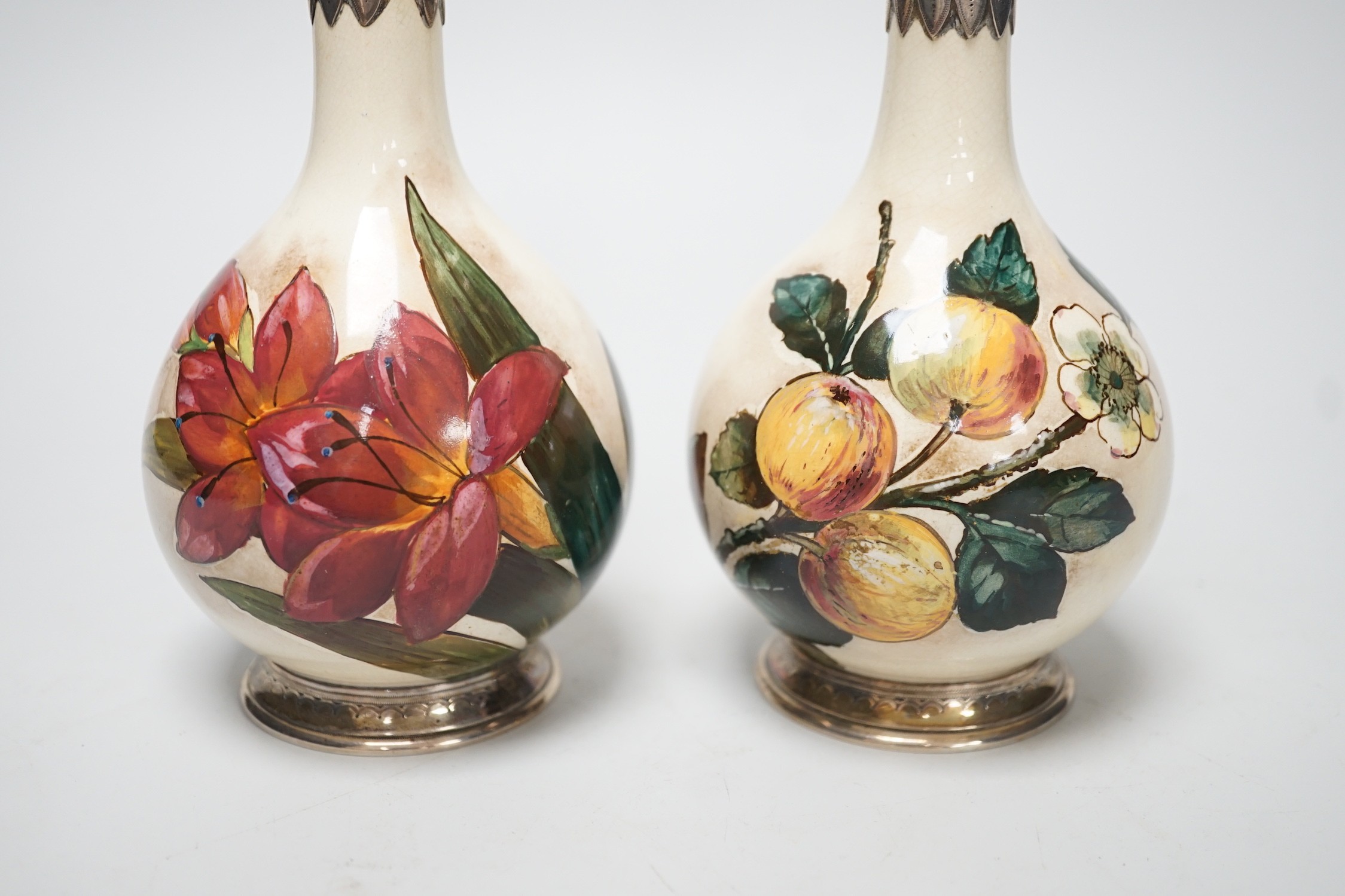 A pair of Victorian silver mounted floral painted earthenware bottle vases. 21cm high